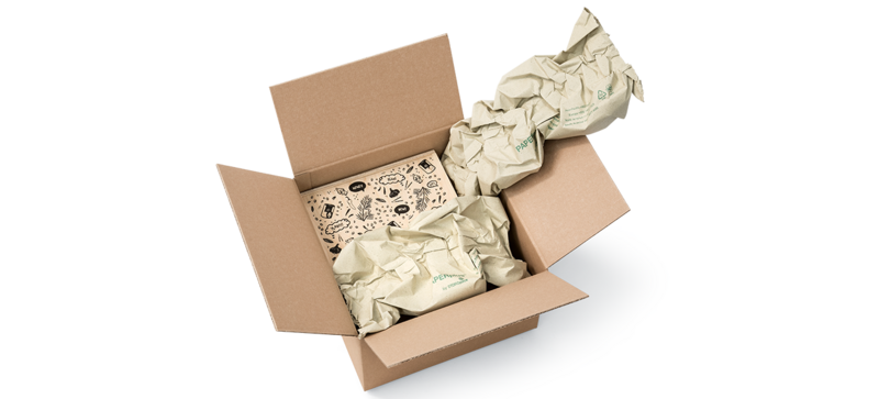 A cardboard box containing a wooden box and paper cushioning strips made from grass paper