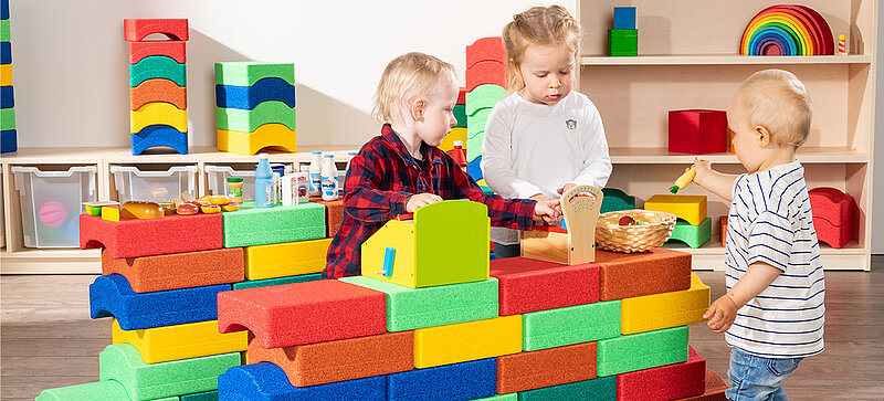 Kinder spielen mit farbigen Spielzeugblöcken