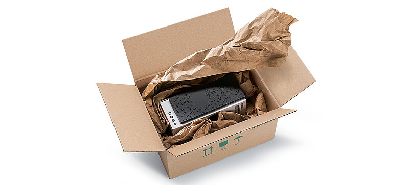 A cardboard box containing technical devices and brown paper cushioning