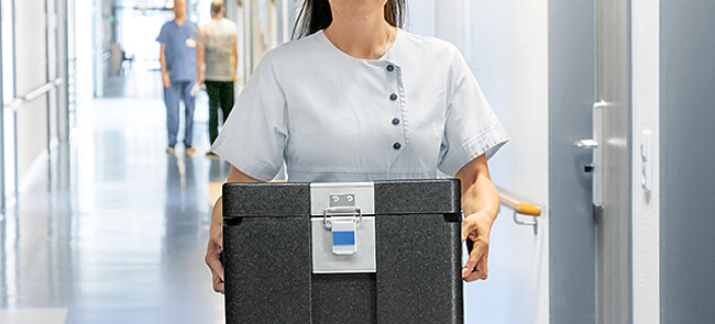 A nurse carrying an insulated box