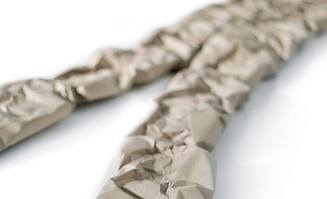 Two paper cushioning strips made from grass paper