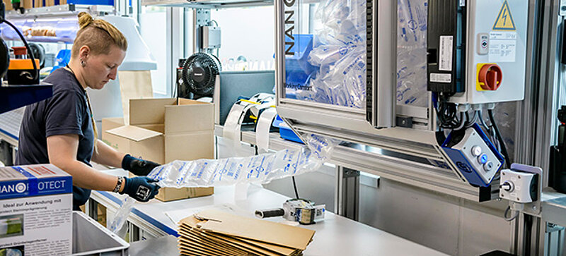 
		Worker using an air cushion machine to pack products in a warehouse.