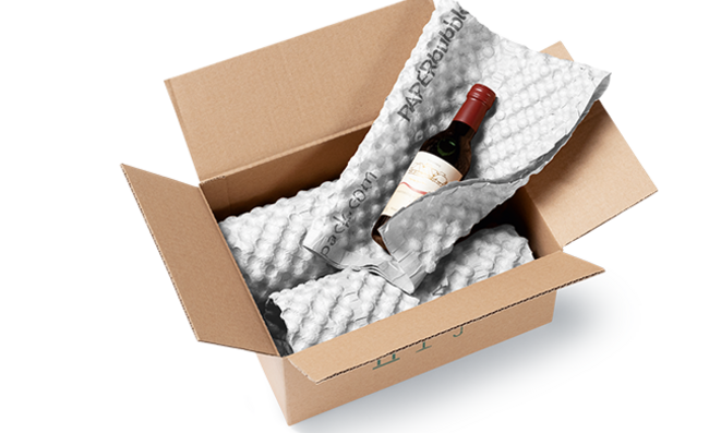 [Translate to International:] Ein Karton mit Weinflaschen, die in weiße Papierpolsterbögen eingewickelt sind