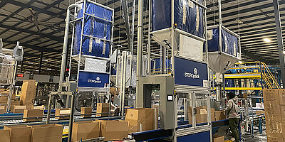 Automated air cushion packaging machines in a large warehouse.