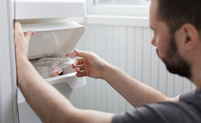 Man throwing something into the trash bin.
