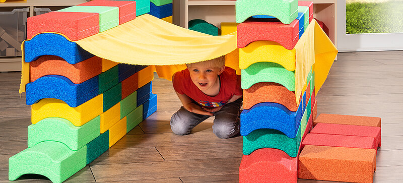 Kinder spielen mit farbigen Spielzeugblöcken