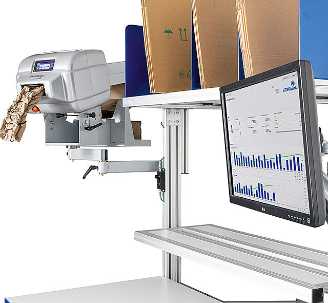 
			Image of a machine with paper next to a monitor and cardboard boxes.