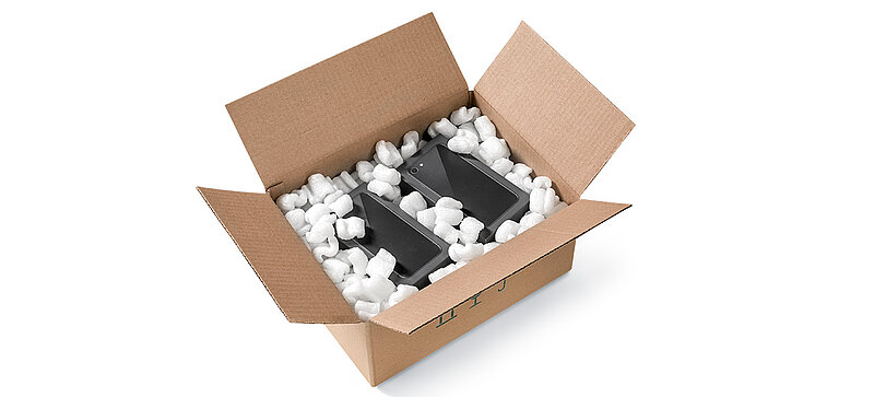 A cardboard box containing smartphones and S-shaped bioplastic packaging chips
